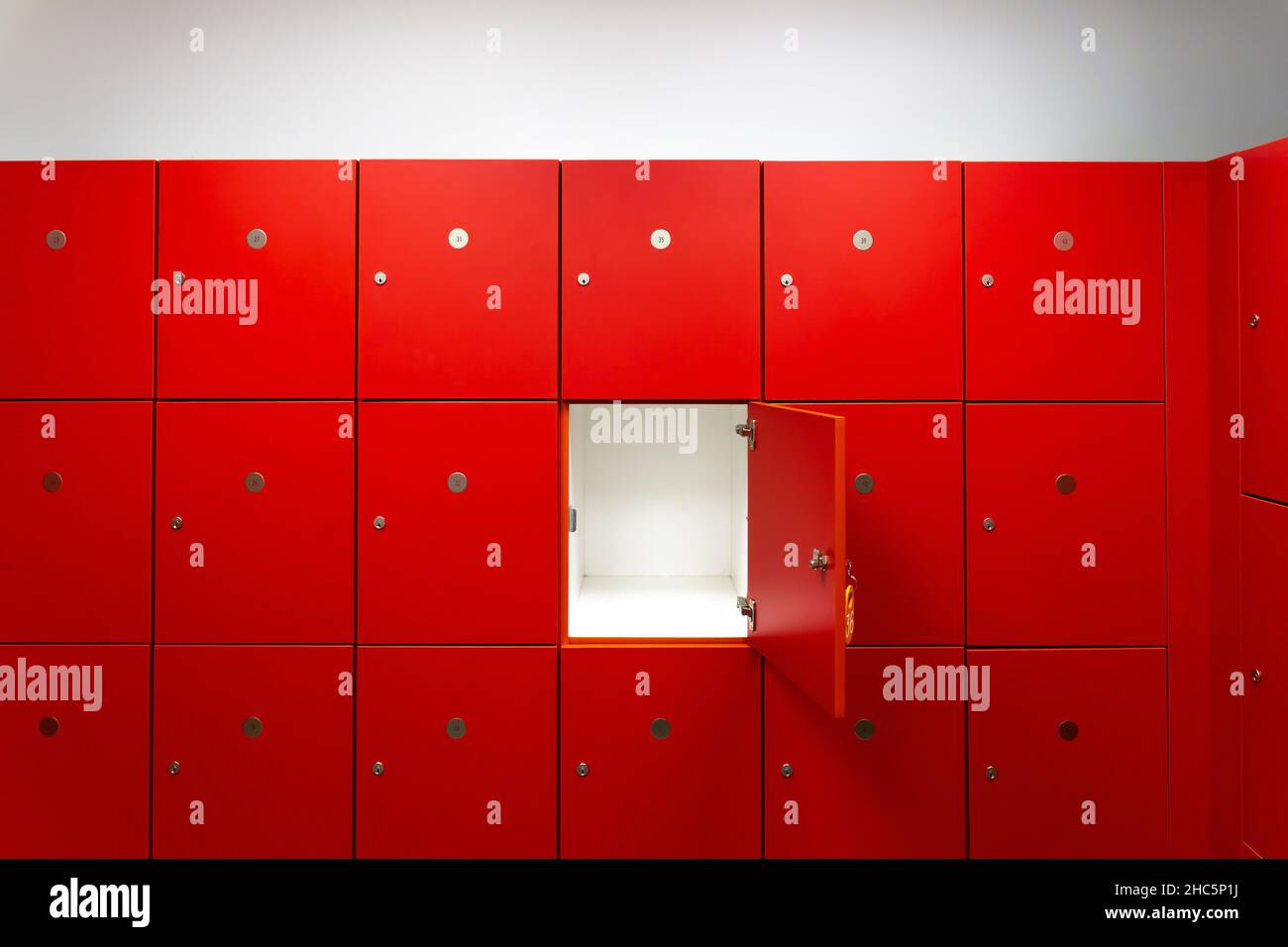 Deponieren Sie rote Schließfächer oder Schließfächer im Fitnessstudio in einem Raum mit einer zentralen, geöffneten Tür Stockfoto