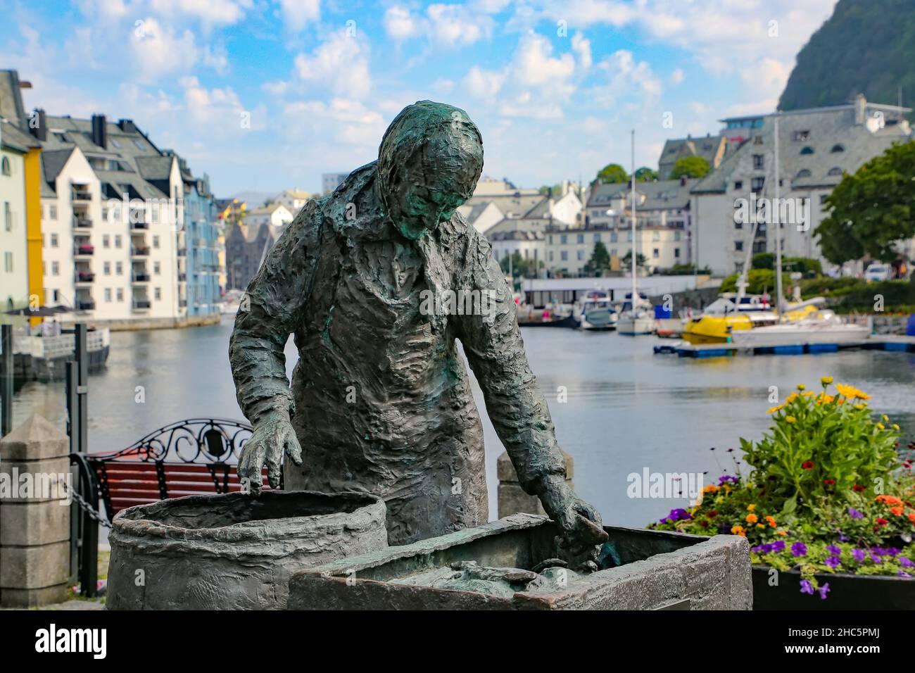 Sildekona (Herringfrau oder Fischdame) Statue mit einem der Kanäle mit Booten und Jugendstilgebäuden im Hintergrund, Alesund, Norwegen. Stockfoto