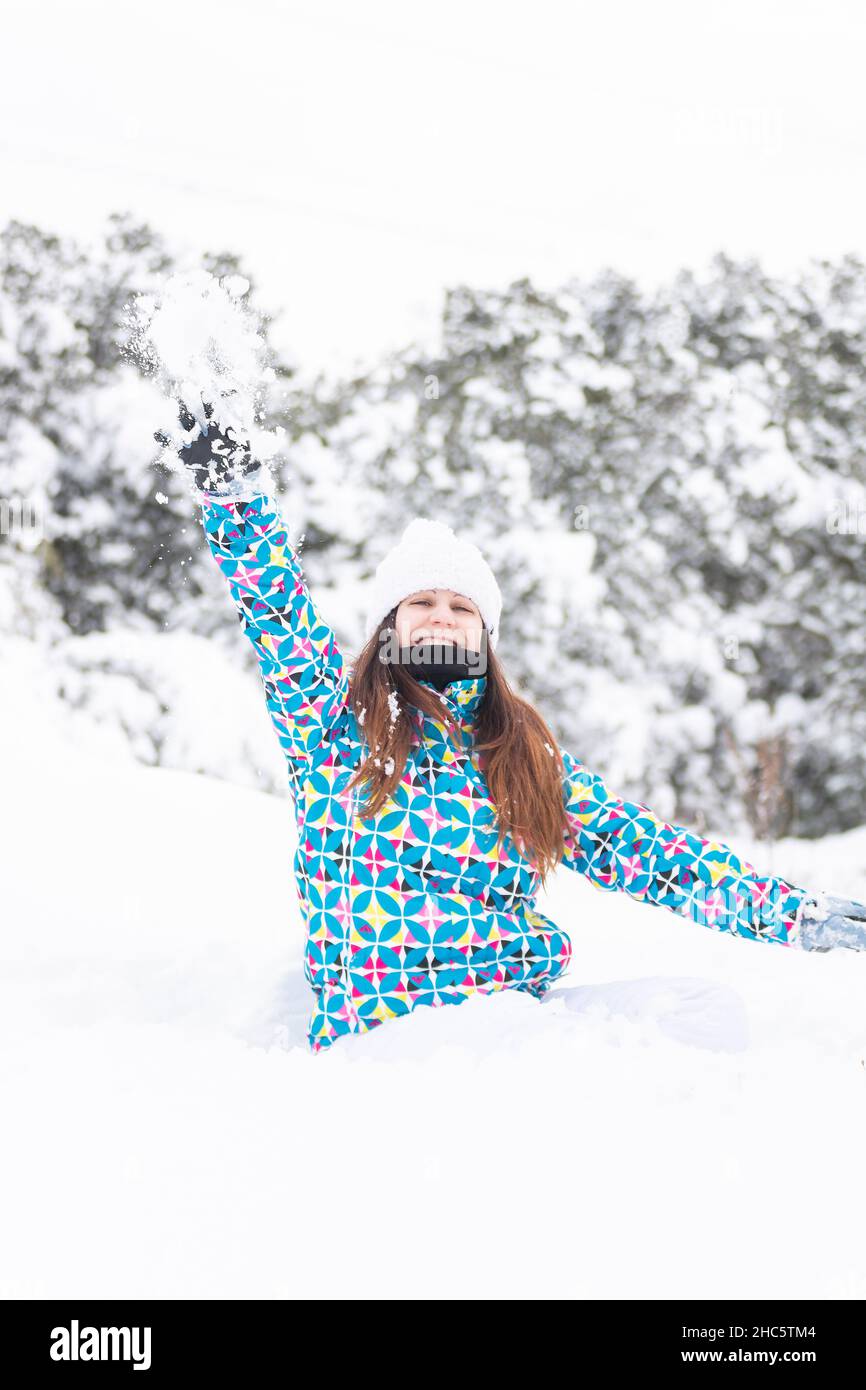 Junge Frau, glücklich, während Sie den Schnee in einem schönen Wald genießen, während des Winters., vertikale Aufnahme Stockfoto