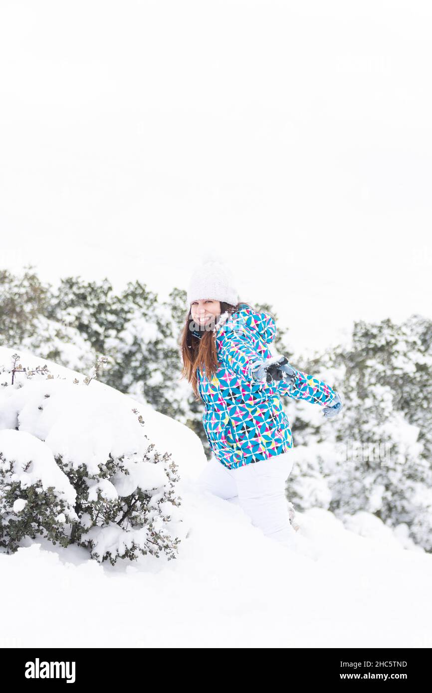 Junge Frau, glücklich, während Sie den Schnee in einem schönen Wald genießen, im Winter, vertikale Aufnahme. Stockfoto