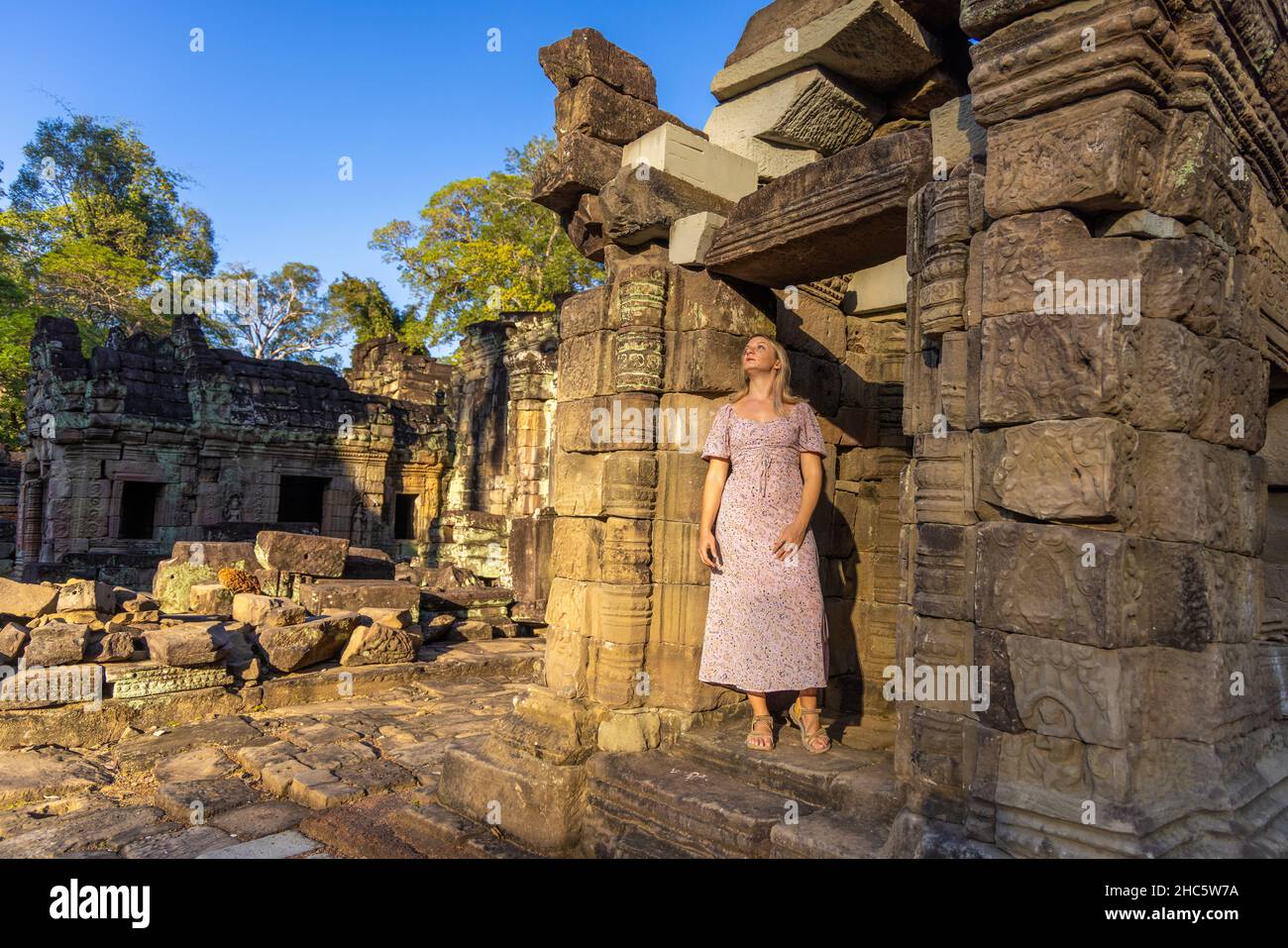 Ein Mädchen in den Ruinen des Ta Prohm Tempels im Angkor Komplex, von Bäumen überwuchert, Kambodscha Stockfoto