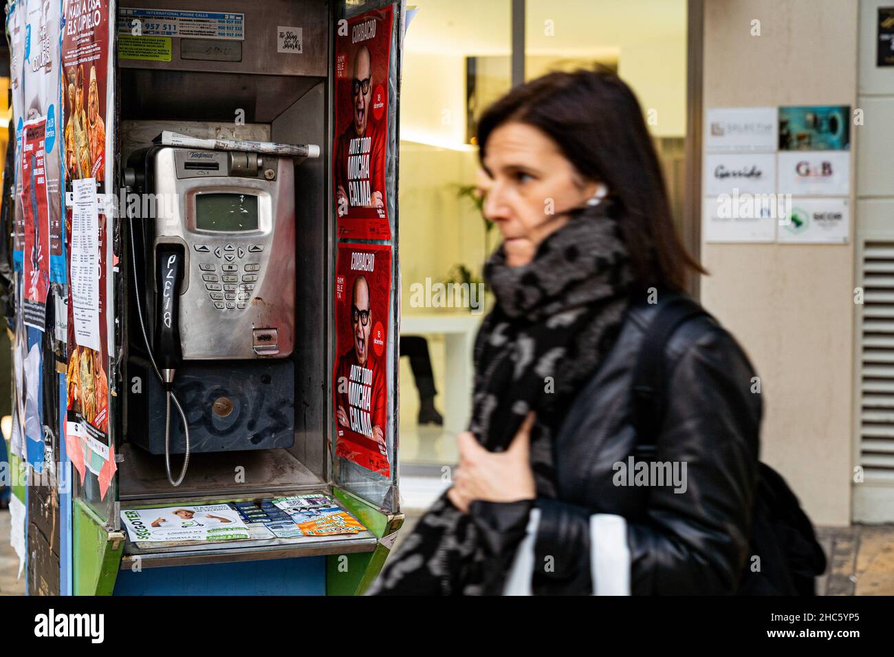 Valencia, Spanien. 15th Dez 2021. Eine Frau kommt vor einer Telefonzelle in Valencia vorbei. Nach dem neuen Allgemeinen Telekommunikationsgesetz (LGT) werden Telefonzellen 2022 verschwinden. Das Aussehen des Mobiltelefons war die Hauptursache für die Nichtnutzung dieser Kabinen. Kredit: SOPA Images Limited/Alamy Live Nachrichten Stockfoto