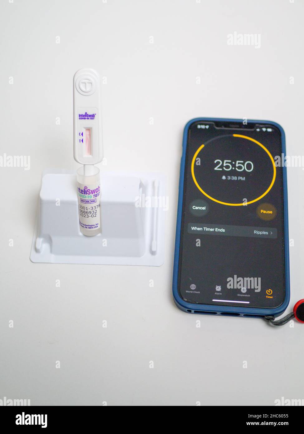 COVID-19 Homesantigen-Testkit. Teststäbchen in Reagenzlösung, Mobiltelefon als Timer. Stockfoto