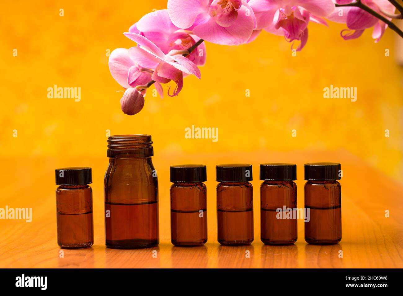 Schöne Aufnahme von Glasflaschen und einer Orchidee auf einem gelben Hintergrund Stockfoto