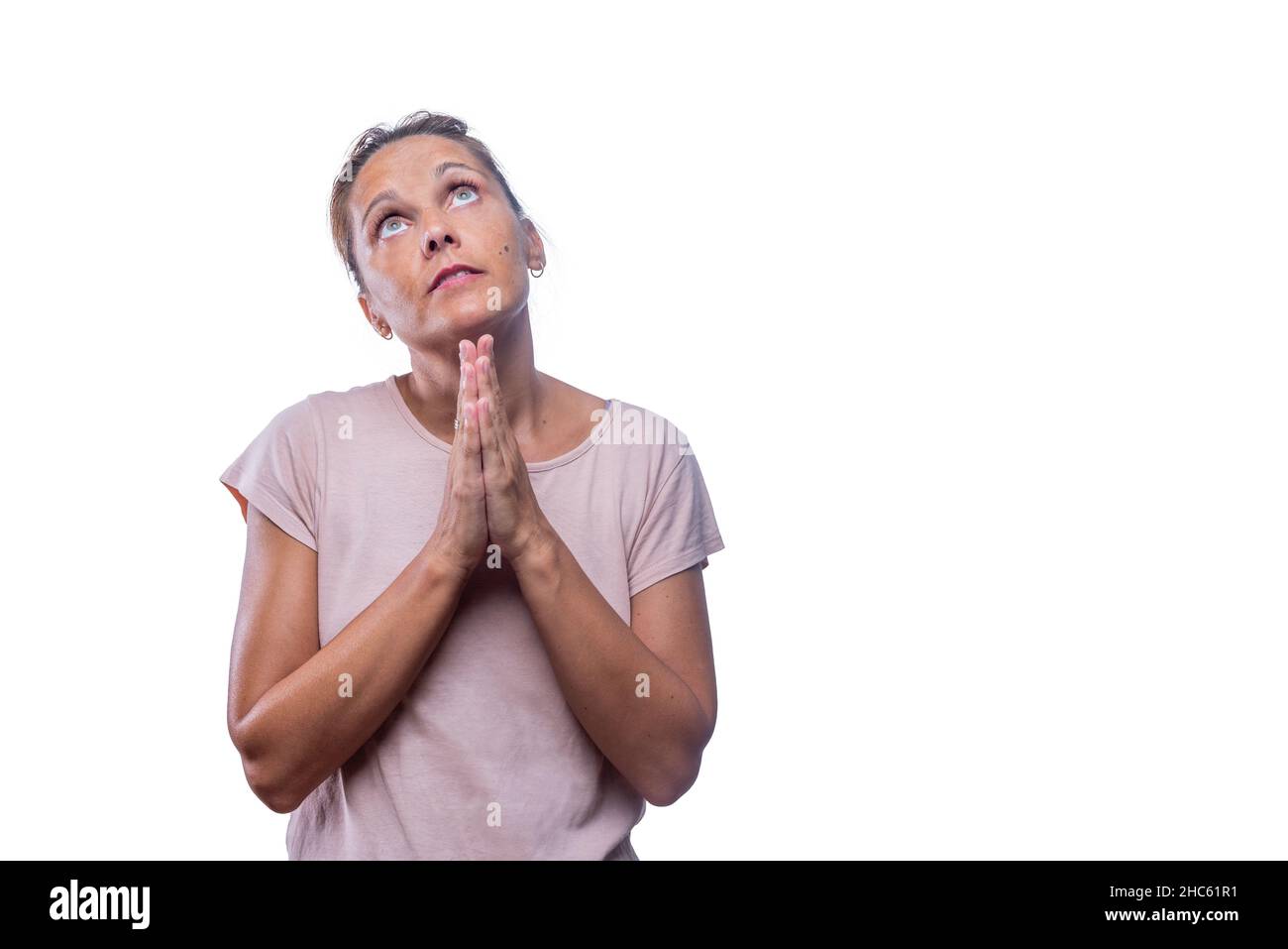 Eine hingebungsvolle Erwachsene Frau, die mit zusammengekrallten Händen betet Stockfoto