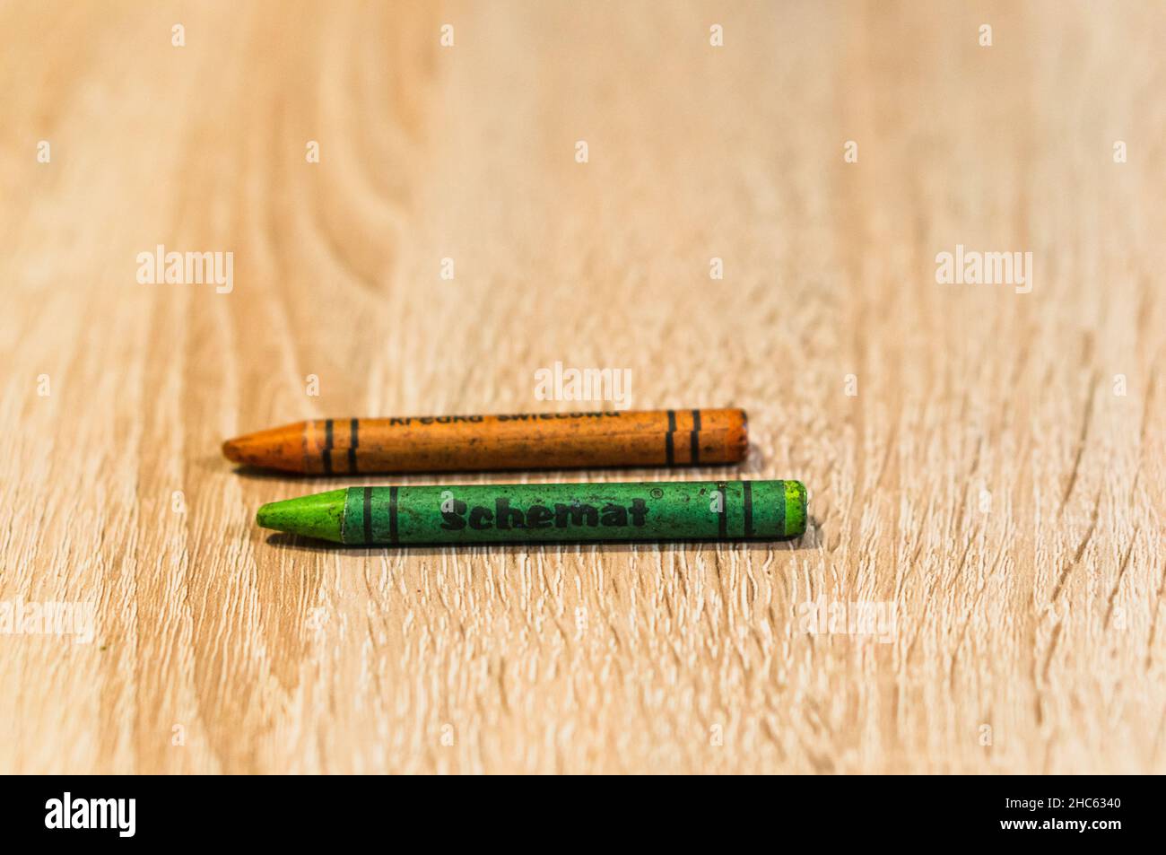Grüne und orange gefärbte Wachsmalstift der Marke Sebamat auf einem Holztisch Stockfoto