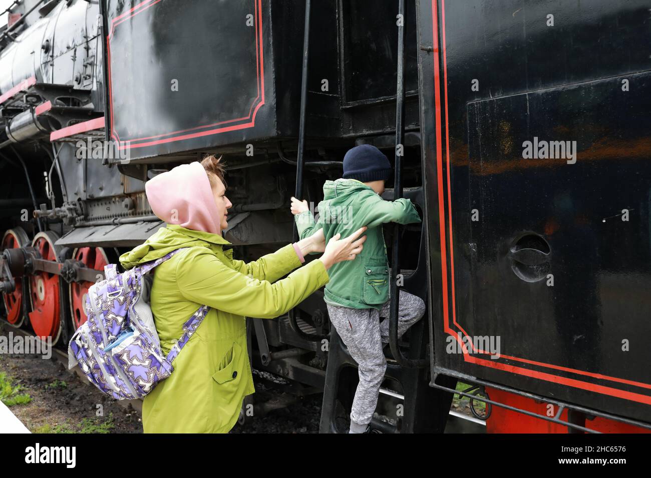 Mutter hilft ihrem Sohn, am Bahnhof auf die Lokomotive zu steigen Stockfoto