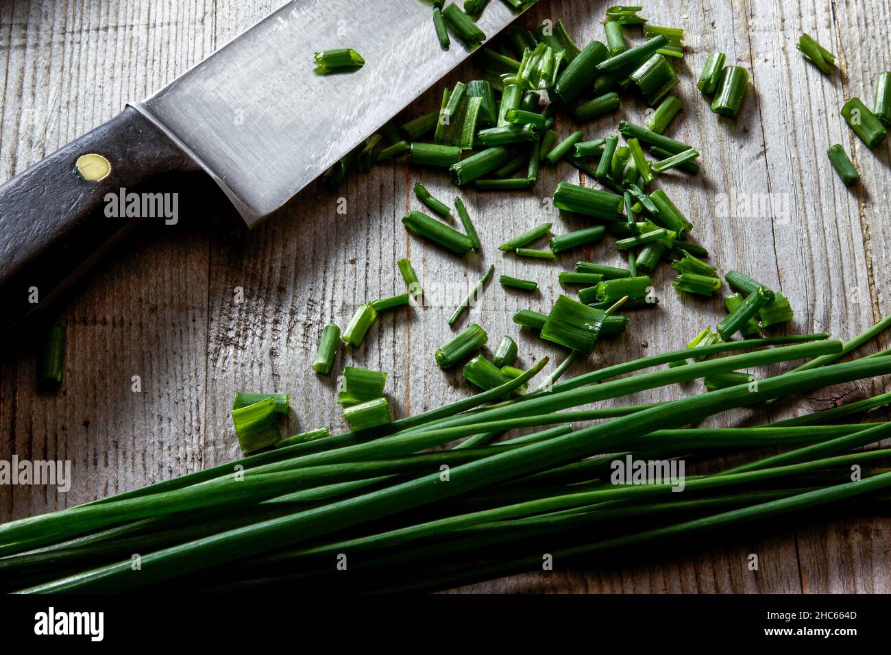 Küchenmesser mit geschnittenem Lauch auf Holzhintergrund Stockfoto