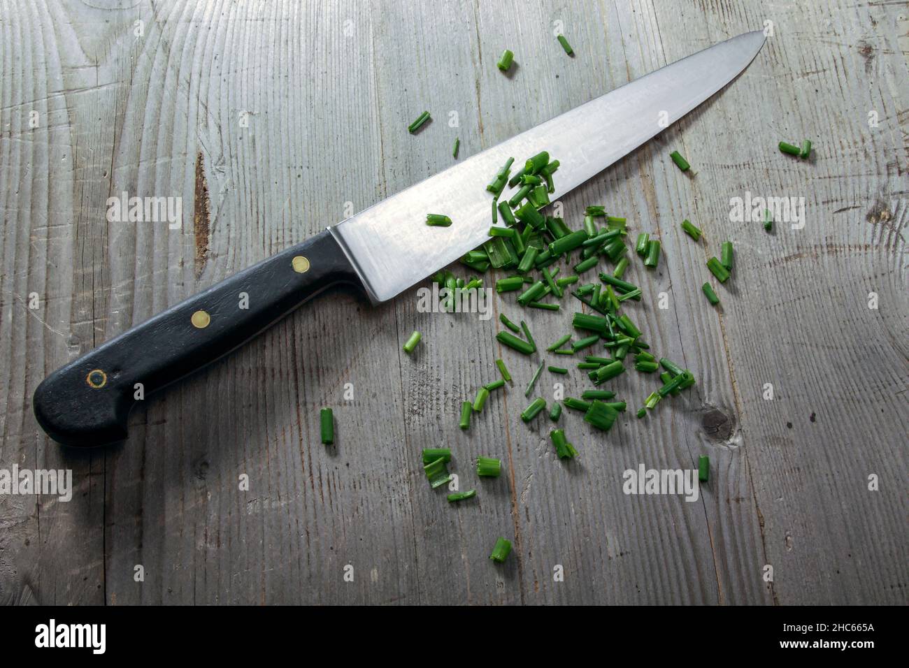 Küchenmesser mit geschnittenem Lauch auf Holzhintergrund Stockfoto