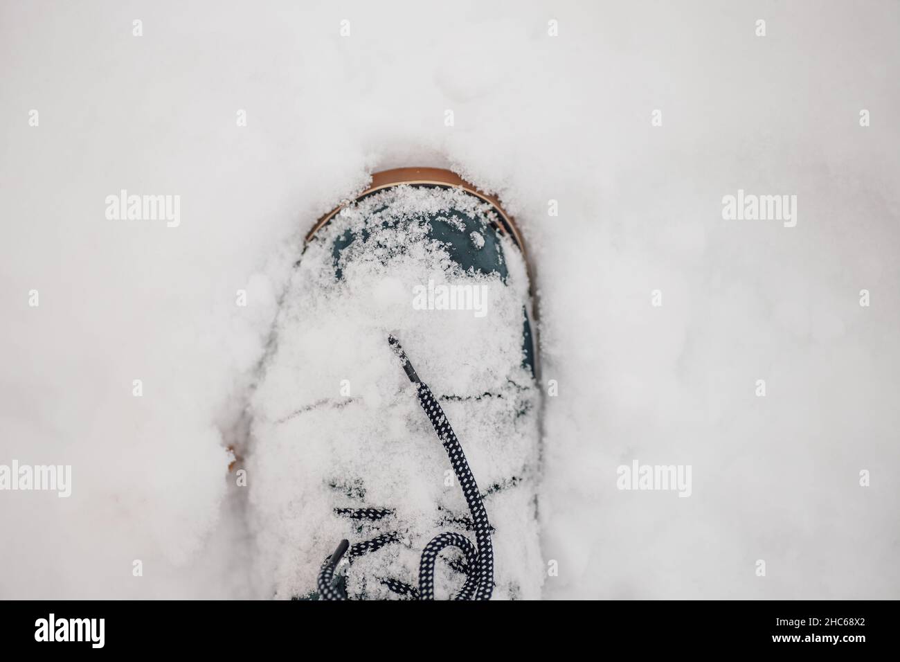 Nahaufnahme des warmen Winterstiefels in Blau mit Schnürsenkeln im Schnee, wodurch die Fußabdruck auf dem mit Schnee bedeckten Boden erreicht wird. Erstaunlicher Hintergrund voller Weiß und Stockfoto