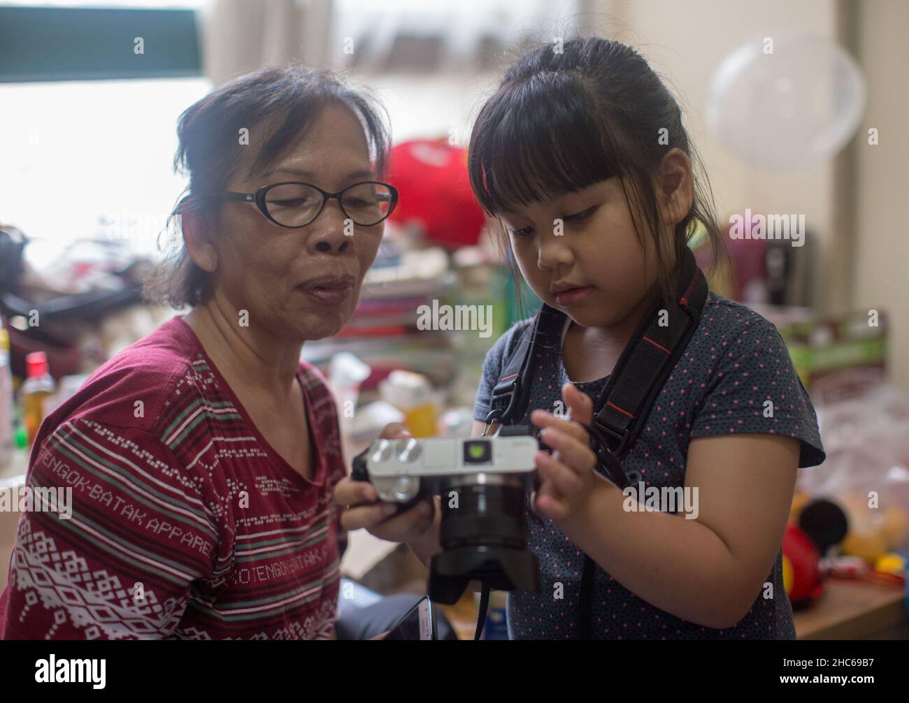 Ein indonesisches Mädchen zeigt ihrer Großmutter in einer Wohnung in Shanghai ein Foto von ihrer Kamera (Sony A6000 Camera & Sony E 35mm F1,8 Objektiv) Stockfoto