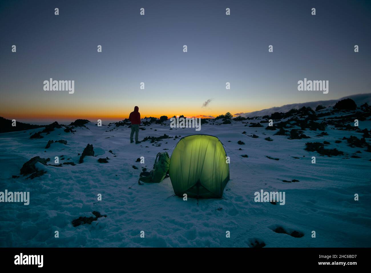 Wild Camping auf dem Schnee des Ätna Mountain man und beleuchtete Zelt bei  Sonnenuntergang, Sizilien Stockfotografie - Alamy