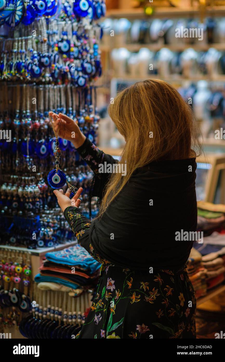 Vertikale Aufnahme einer blonden Frau, die türkische Souvenirs im Großen Basar von Istanbul berührt Stockfoto