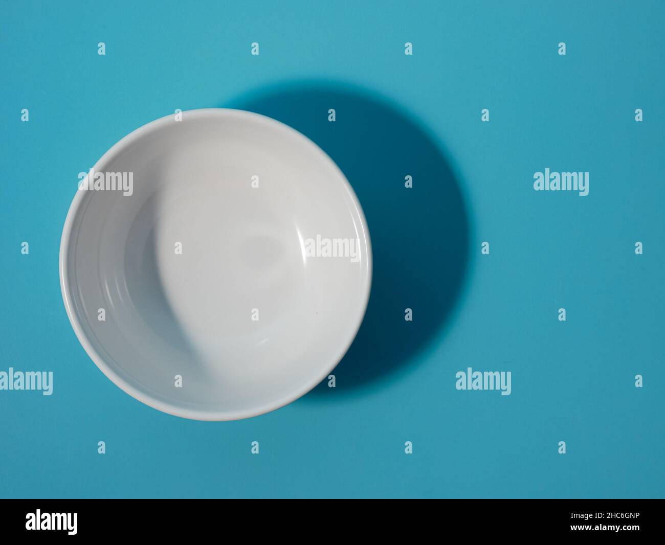 Leere weiße Schale auf blauem Hintergrund. Minimalistischer Stil. Stockfoto