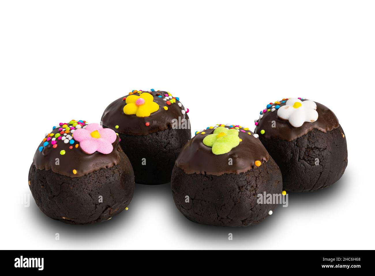 Seitenansicht der hausgemachten Schokoladenkugeln mit bunten Regenbogenstreuseln und Zuckerblume auf weißem Hintergrund mit Schneideweg. Stockfoto