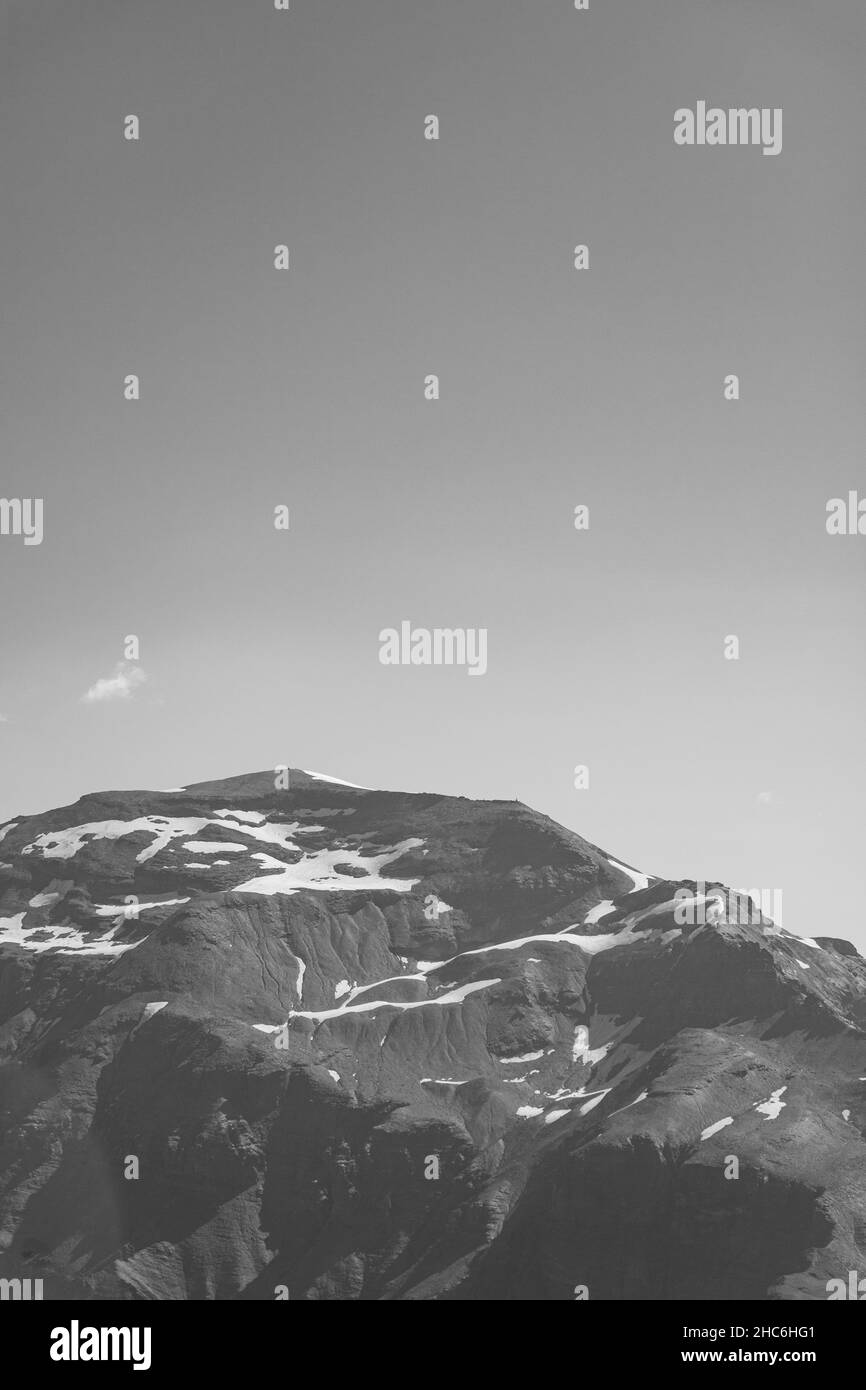 Vertikale Graustufenaufnahme von verschneiten Berggipfeln Stockfoto