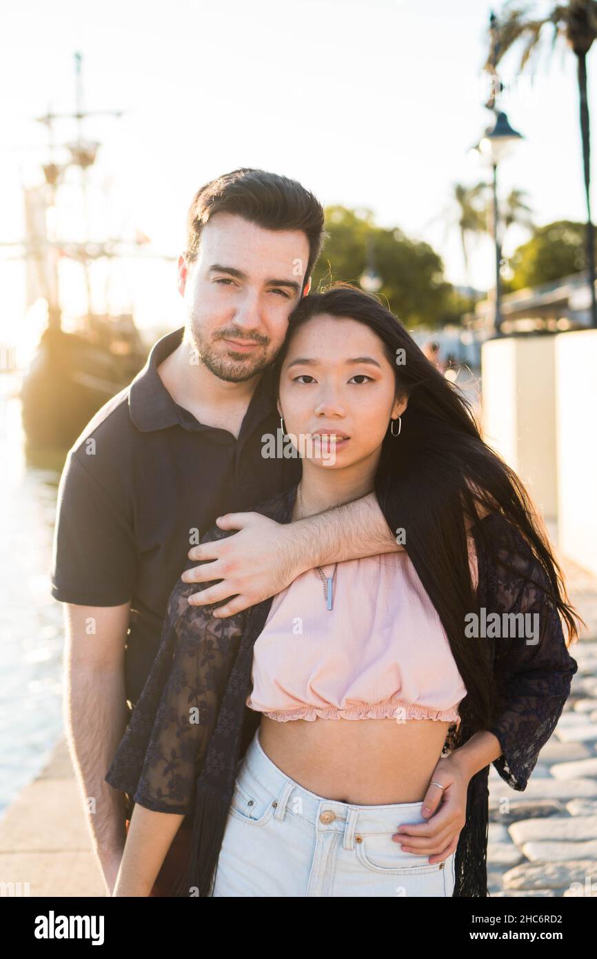Romantisches interracial Paar Blick auf Kamera. Freund und asiatische Freundin im Freien mit einem Sonnenuntergang Stockfoto