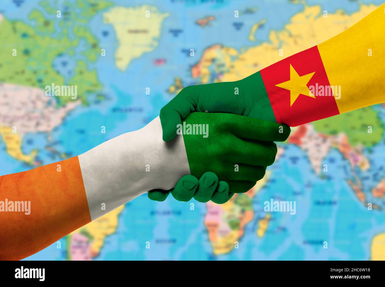 Handschlag zwischen Kamerun und Côte d'Ivoire Flaggen auf Händen gemalt.mit Hintergrund der Weltkarte Stockfoto