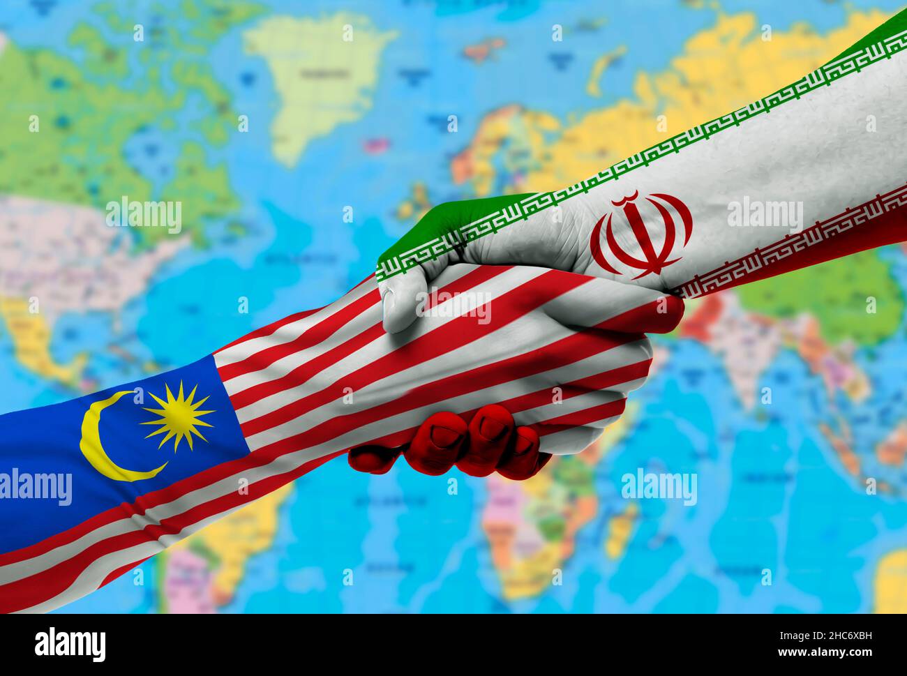 Handschlag zwischen Malaysia und Iran Flaggen auf Händen gemalt.mit Hintergrund der Weltkarte Stockfoto