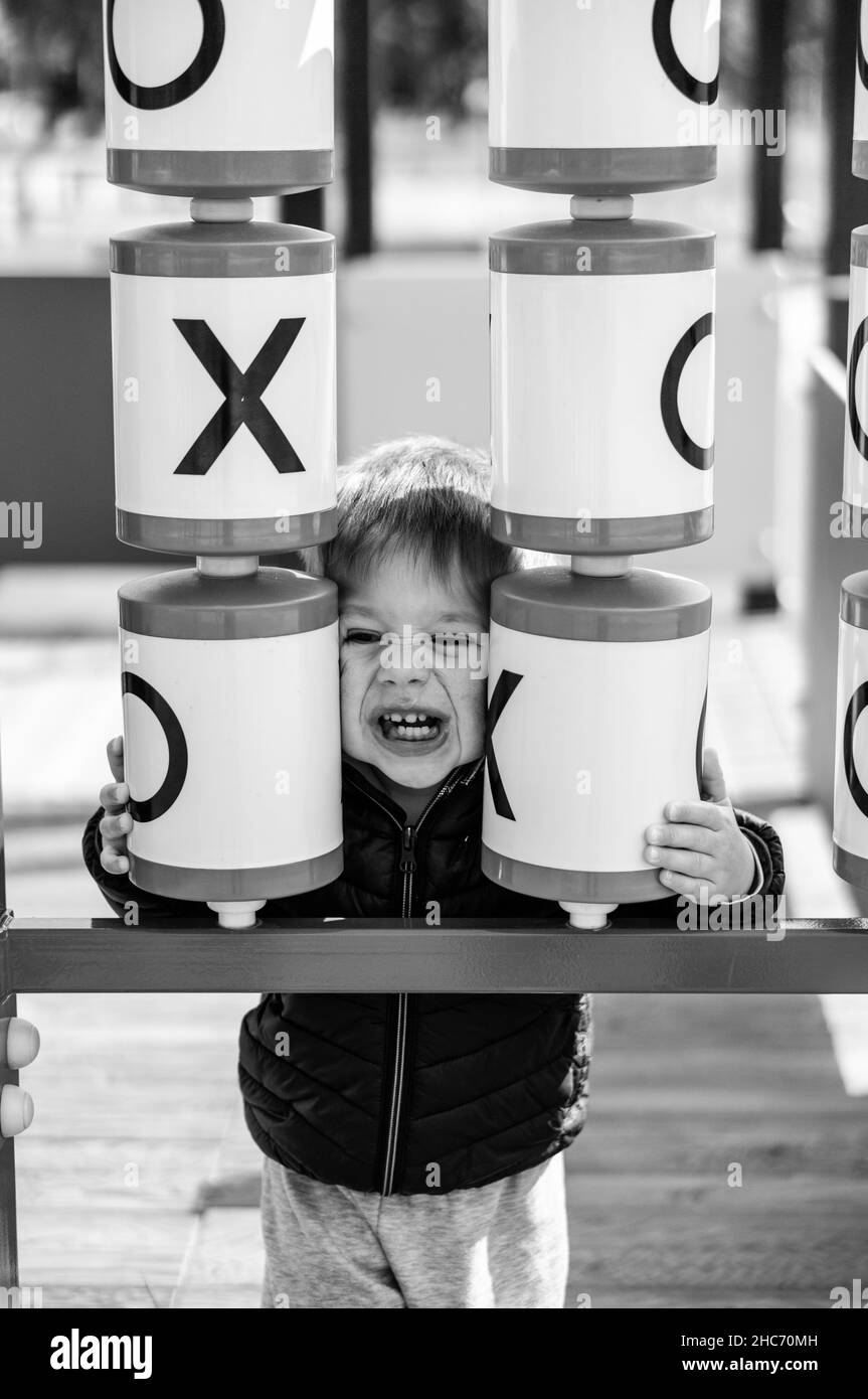 Vertikale Graustufenaufnahme eines lachenden polnischen Kindes auf dem Spielplatz Stockfoto