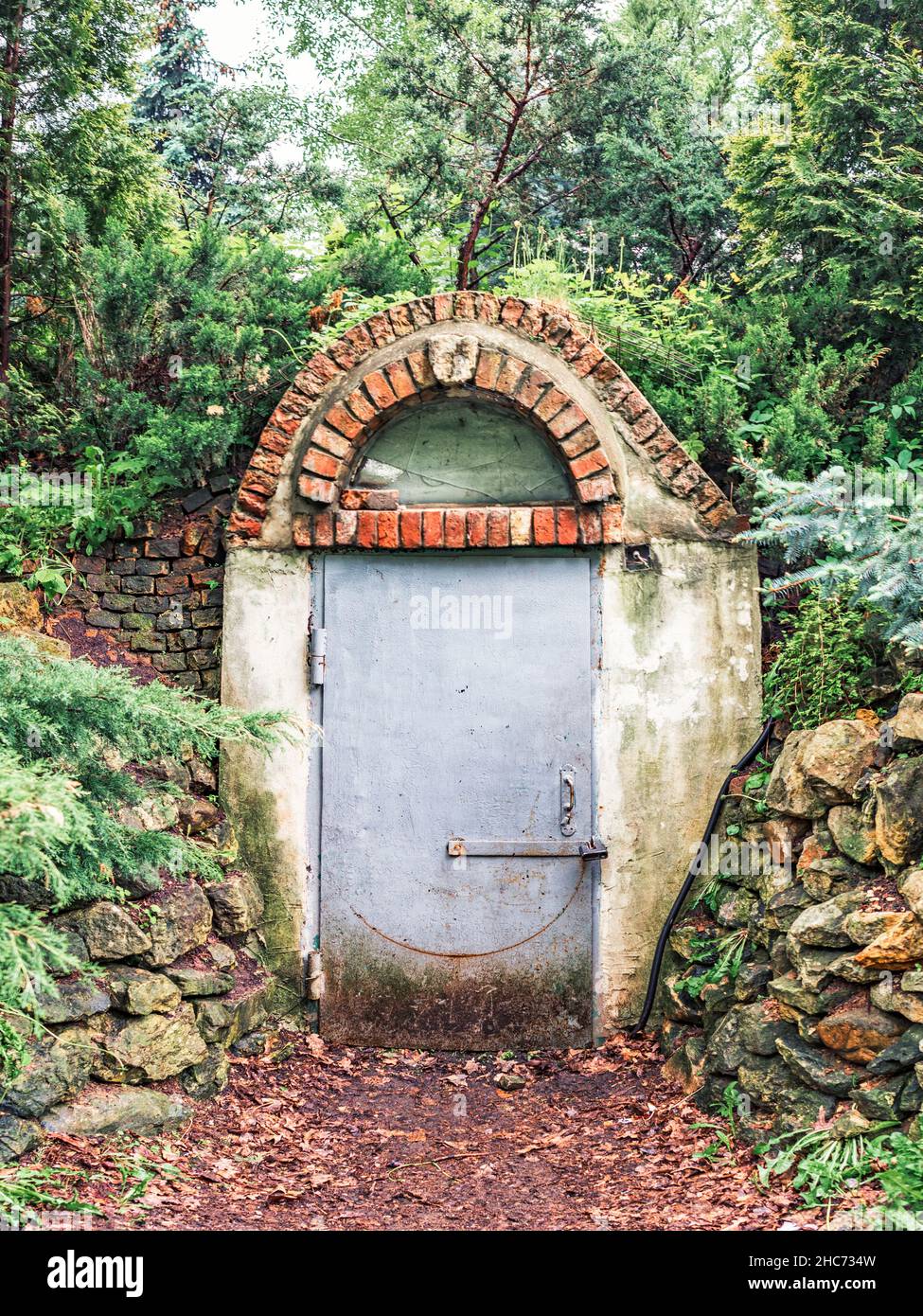 Eingang zu einem alten Ziegelbunker im Wald mit einer Metalltür Stockfoto