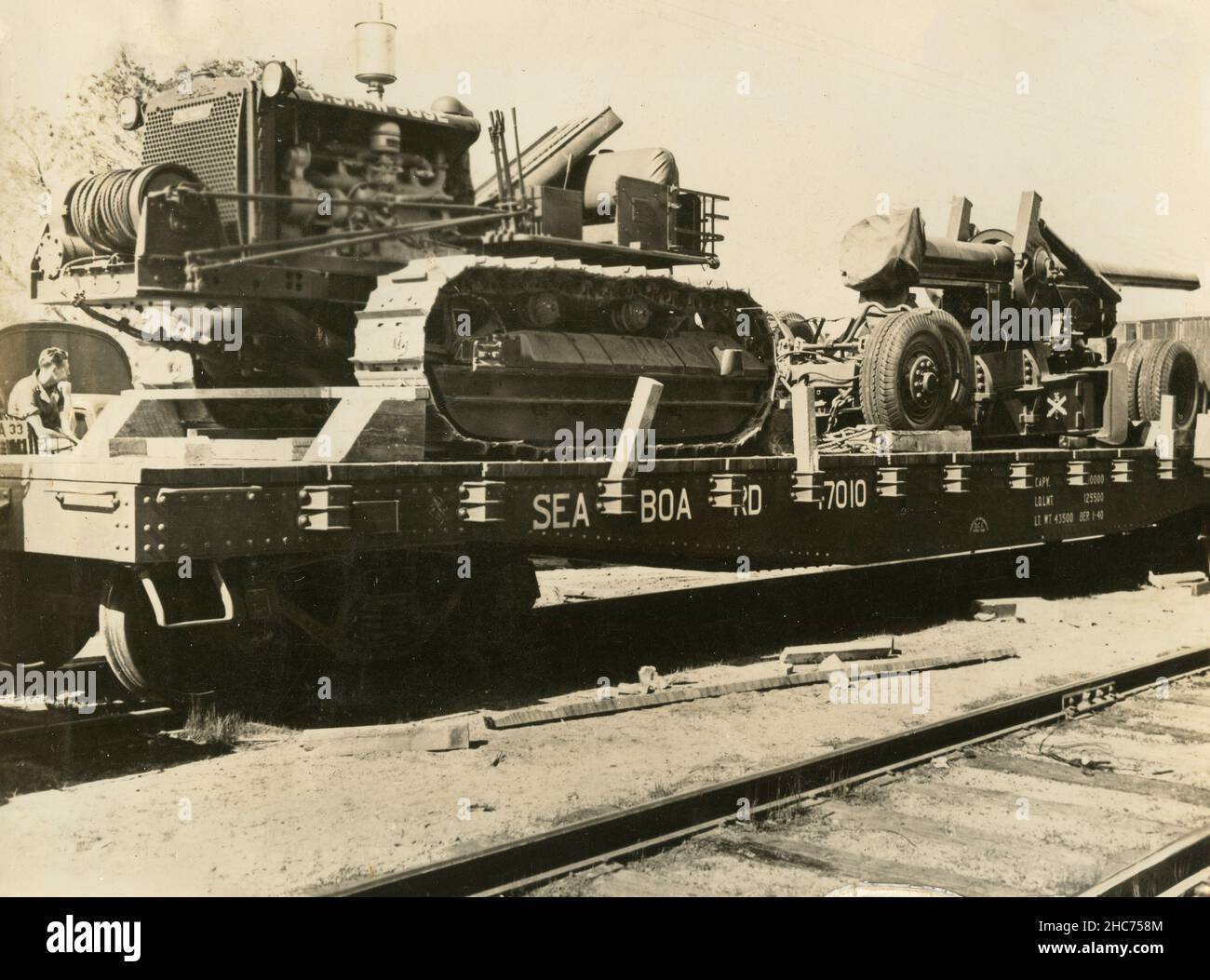 Ein Caterpillar-Traktor der US-Armee und eine 155mm-Pistole auf einem einzigen flachen Wagen des US Railroad Transport, USA 1940s Stockfoto