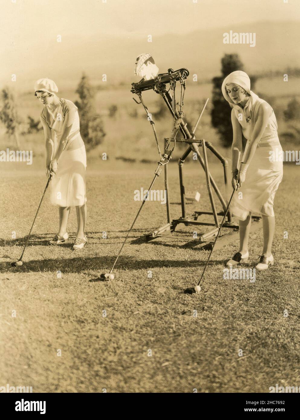 Zwei Mädchen spielen Golf mit einem automatischen Trainer, USA 1930s Stockfoto