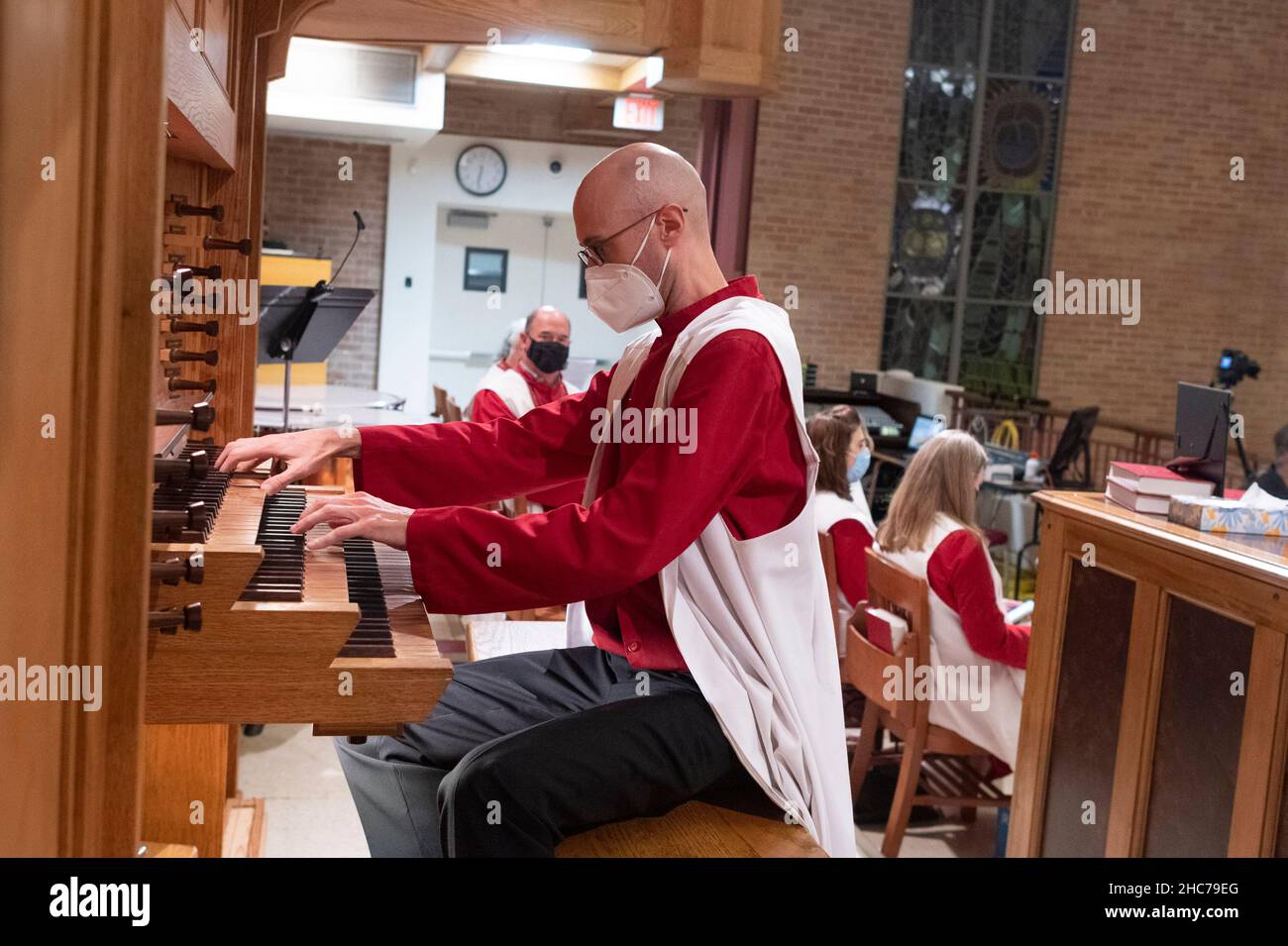 Austin, Texas, USA. 24th Dez 2021. Organist AUSTIN HALLER spielt während der Weihnachtsfeier in der Lutherischen Kirche Saint Martin vollständig maskiert. Die mehr als 136 Jahre alte Kirche dient in ihrem modernen Gebäude aus der Mitte des Jahrhunderts in der Innenstadt von Austin, Texas, einer vielfältigen Bevölkerung. Kredit: Bob Daemmrich/Alamy Live Nachrichten Stockfoto