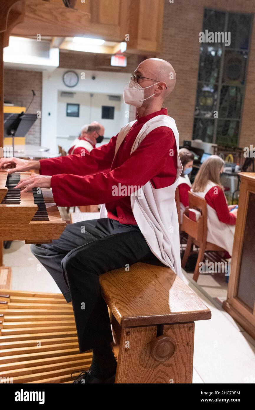 Austin, Texas, USA. 24th Dez 2021. Organist AUSTIN HALLER spielt während der Weihnachtsfeier in der Lutherischen Kirche Saint Martin vollständig maskiert. Die mehr als 136 Jahre alte Kirche dient in ihrem modernen Gebäude aus der Mitte des Jahrhunderts in der Innenstadt von Austin, Texas, einer vielfältigen Bevölkerung. Kredit: Bob Daemmrich/Alamy Live Nachrichten Stockfoto