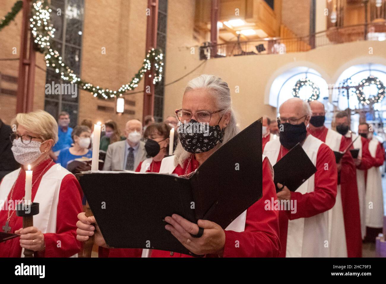 Austin, Texas, USA. 24th Dez 2021. Das Chormitglied JUDY BEGLAU tritt während der Heiligabend-Gottesdienste in der Lutherischen Kirche St. Martin vollständig maskiert in das Heiligtum ein. Die Kirche, ein Mitglied der Evangelisch-Lutherischen Kirche von Amerika (ELCA), ist mehr als 136 Jahre alt und dient in ihrem modernen Gebäude aus der Mitte des Jahrhunderts in der Innenstadt von Austin, Texas, einer vielfältigen Bevölkerung. Kredit: Bob Daemmrich/Alamy Live Nachrichten Stockfoto