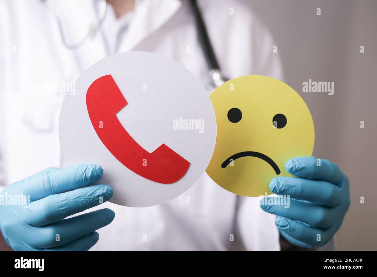 Nahaufnahme eines Arztes mit einem Smiley mit trauriger Emotion und einem Telefonanrufsymbol Stockfoto