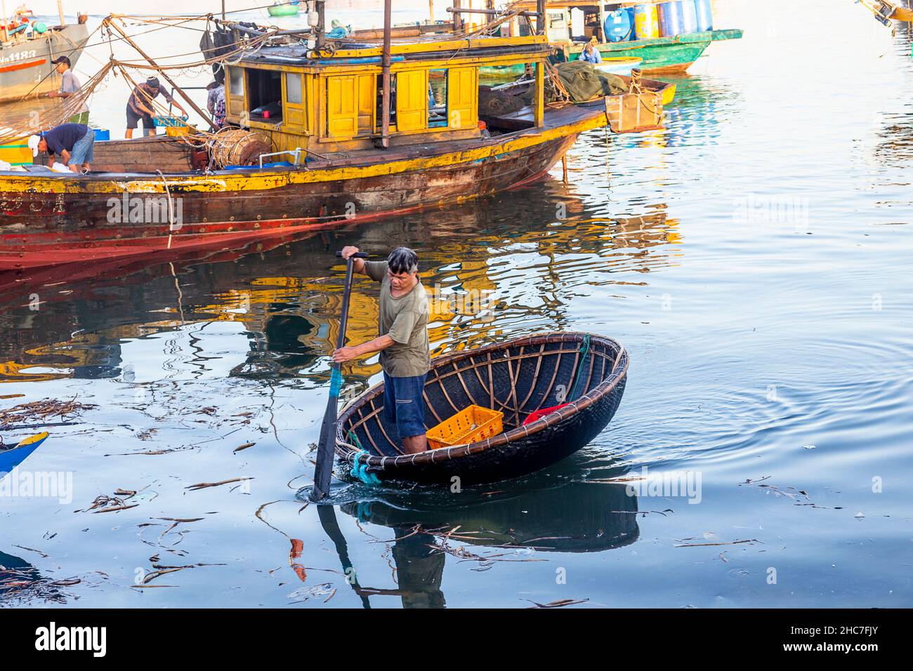 Der Mensch nutzt ein Ruder, um in seinem Korbboot vom Nachtfischen an Land zu kommen. Stockfoto