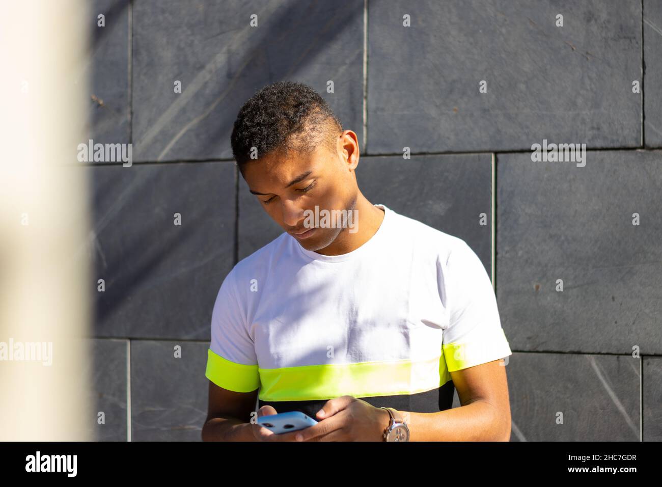 Junger Latino mit Handy auf der Straße Stockfoto
