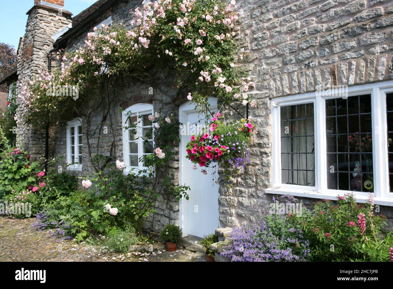 Much Wenlock, Shropshire, England Großbritannien, Juli 17th 2016. Charmantes Steinhaus außen mit Kletterrosen. Stockfoto