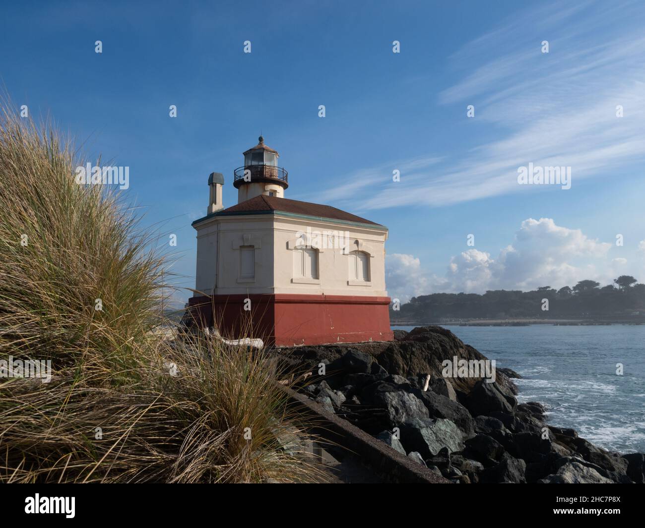 Coquille River oder Bandon Leuchtturm mit Gras im Vordergrund und Wasser im Hintergrund. Stockfoto