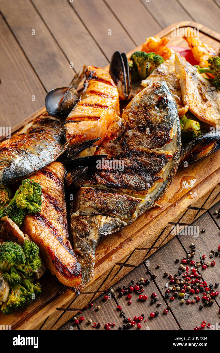 Verschiedene gegrillte Fische auf einem Holzbrett Stockfoto