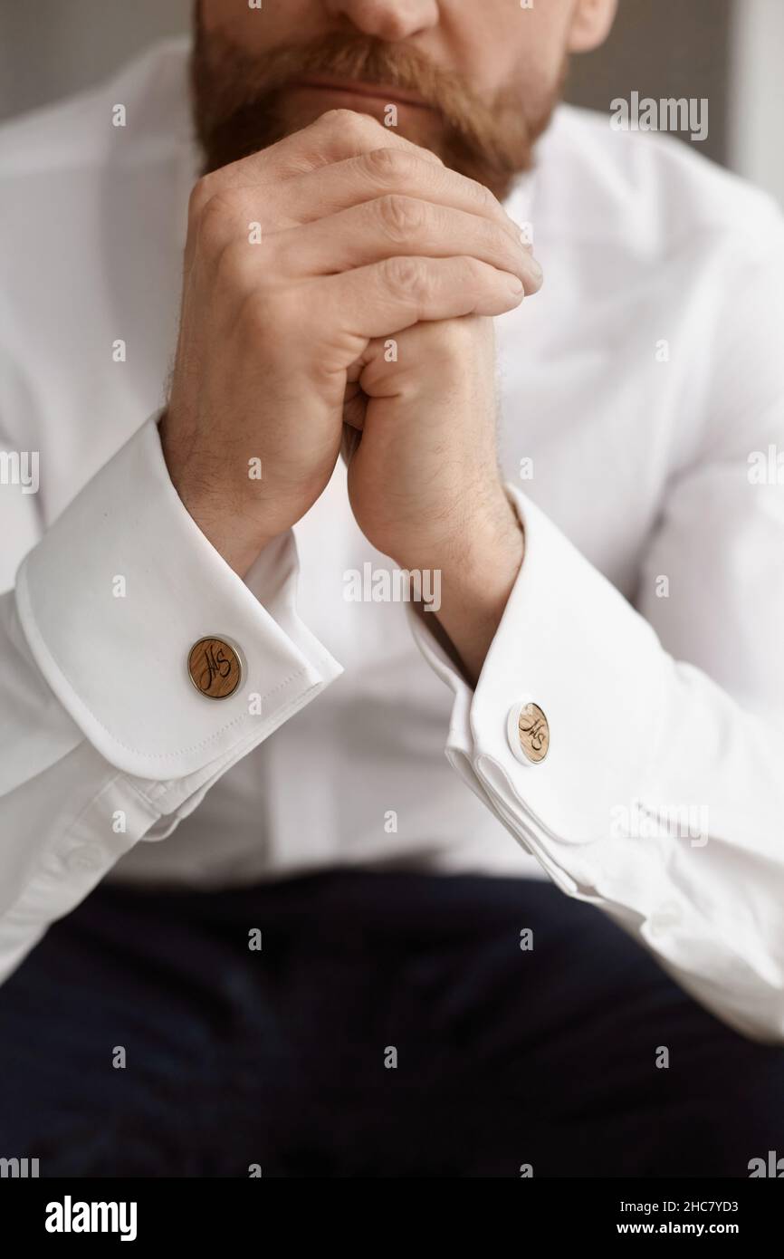 Nahaufnahme eines eleganten, gutaussehenden Mannes, eines jungen bärtigen Geschäftsmannes oder eines stilvollen Bräutigams in einem weißen Hemd mit modischen Manschettenknöpfen auf seinem Hemd Stockfoto