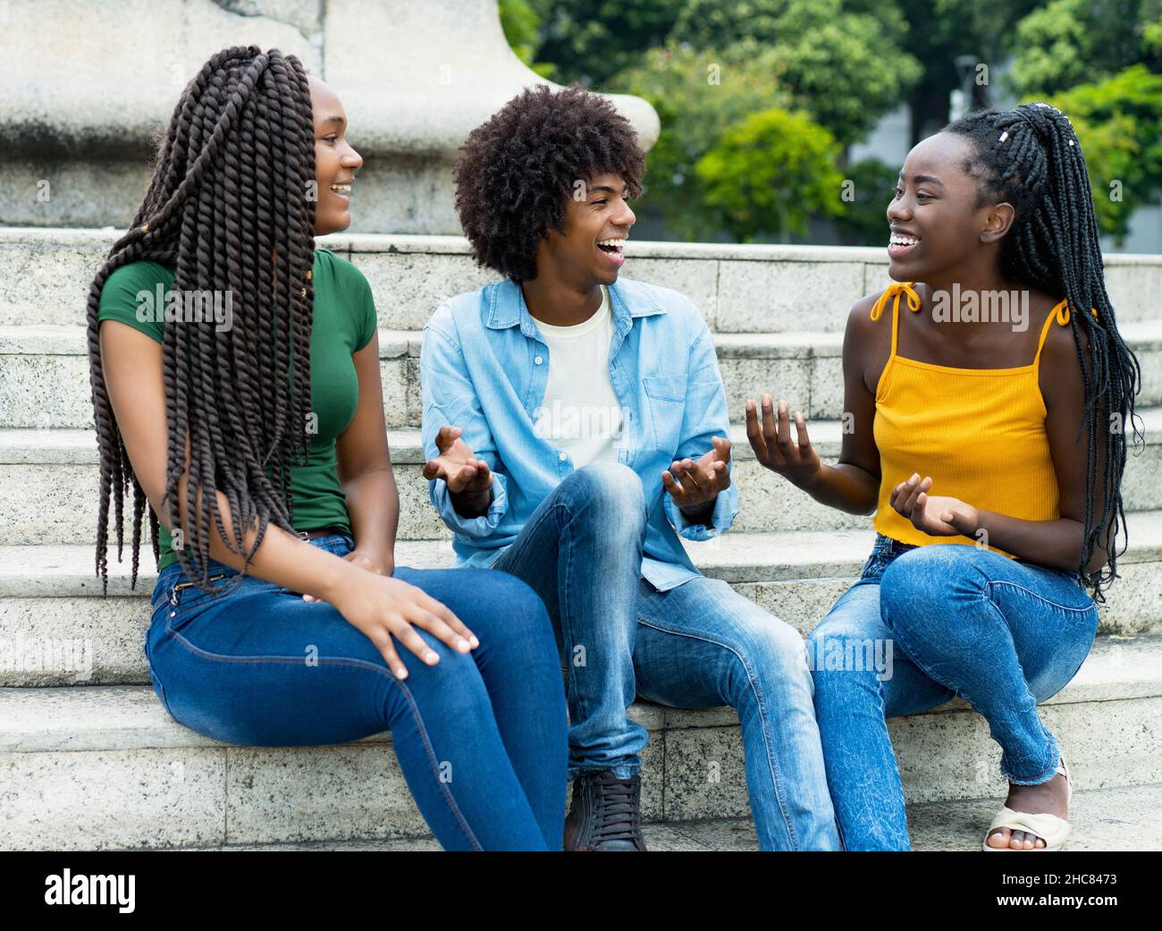 Lachende Gruppe afroamerikanischer weiblicher und männlicher junger Erwachsener im Sommer in der Stadt Stockfoto