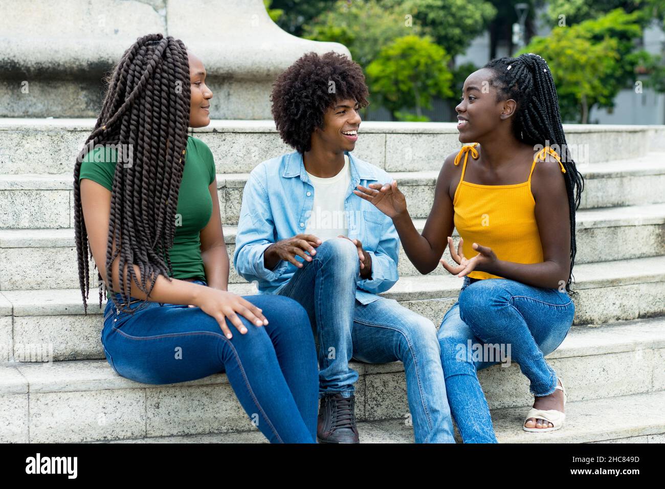 Gruppe afroamerikanischer weiblicher und männlicher junger Erwachsener, die über das Leben im Freien im Sommer in der Stadt sprechen Stockfoto