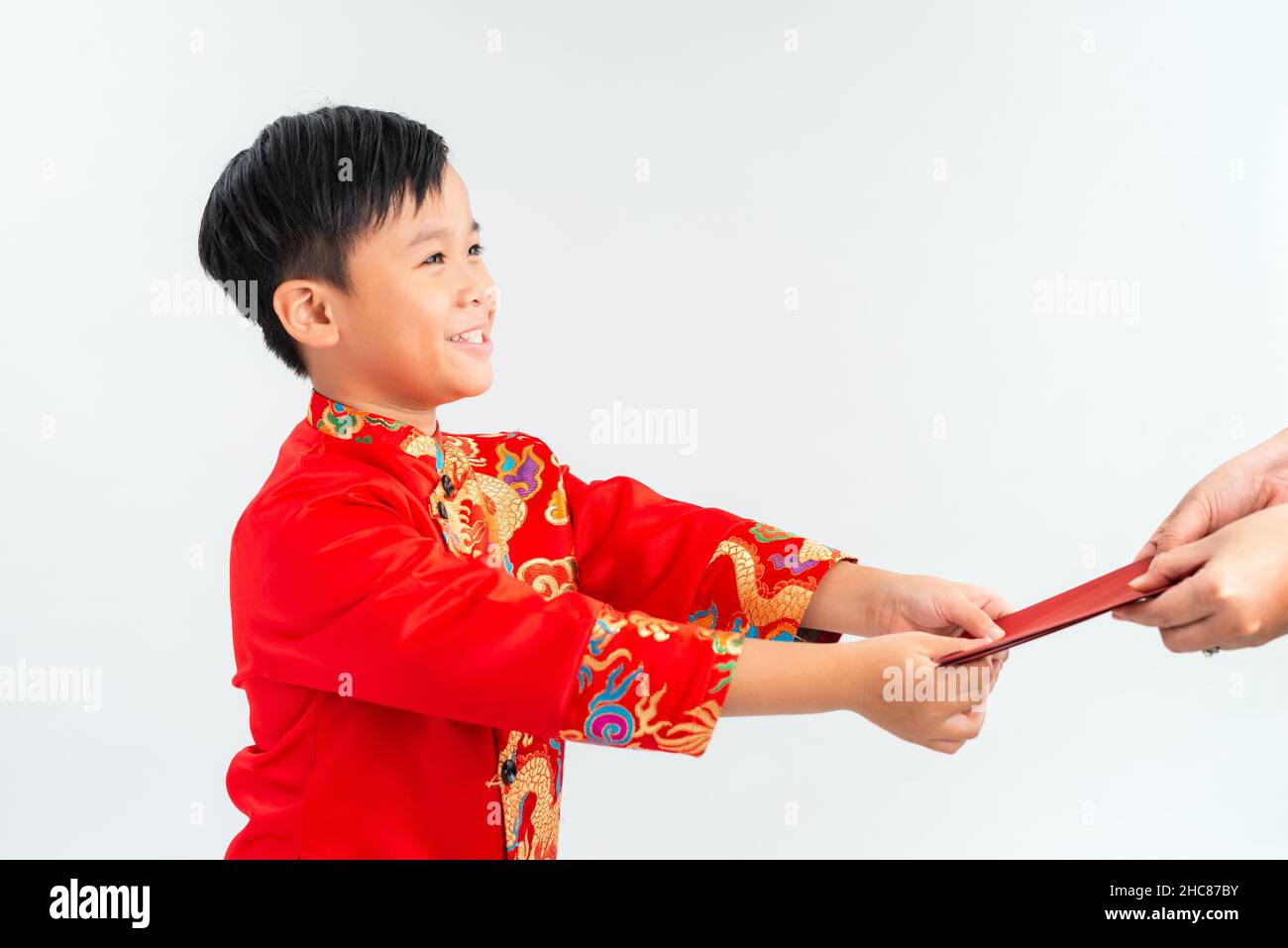 Asiatischer vietnamesischer Junge, der auf dem Mond-Neujahrsfest rote Papiertüten oder Geld von einem anderen erhält, wobei das traditionelle Ao dai auf weißem Hintergrund isoliert ist Stockfoto