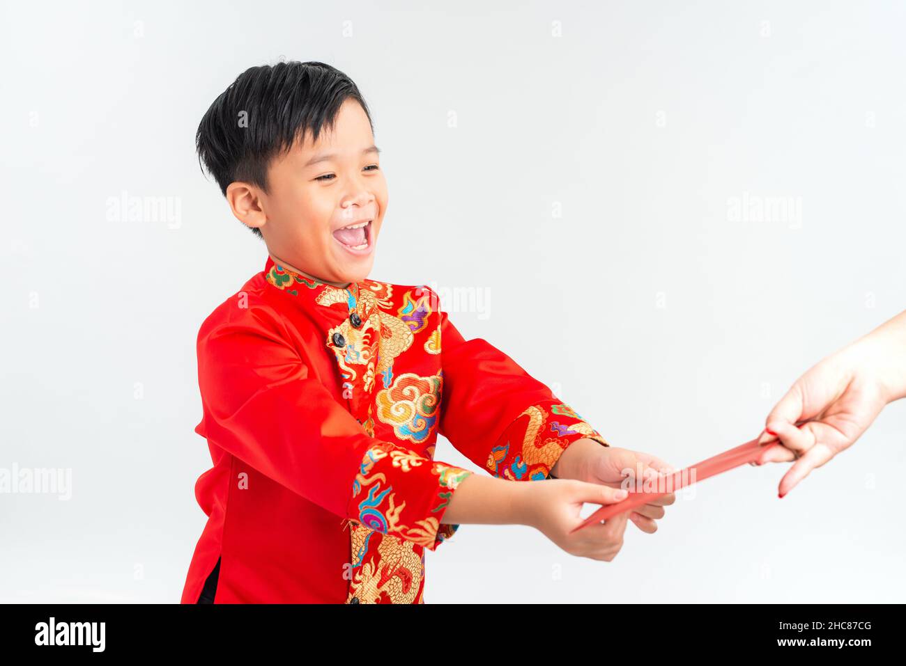 Asiatischer vietnamesischer Junge, der auf dem Mond-Neujahrsfest rote Papiertüten oder Geld von einem anderen erhält, wobei das traditionelle Ao dai auf weißem Hintergrund isoliert ist Stockfoto