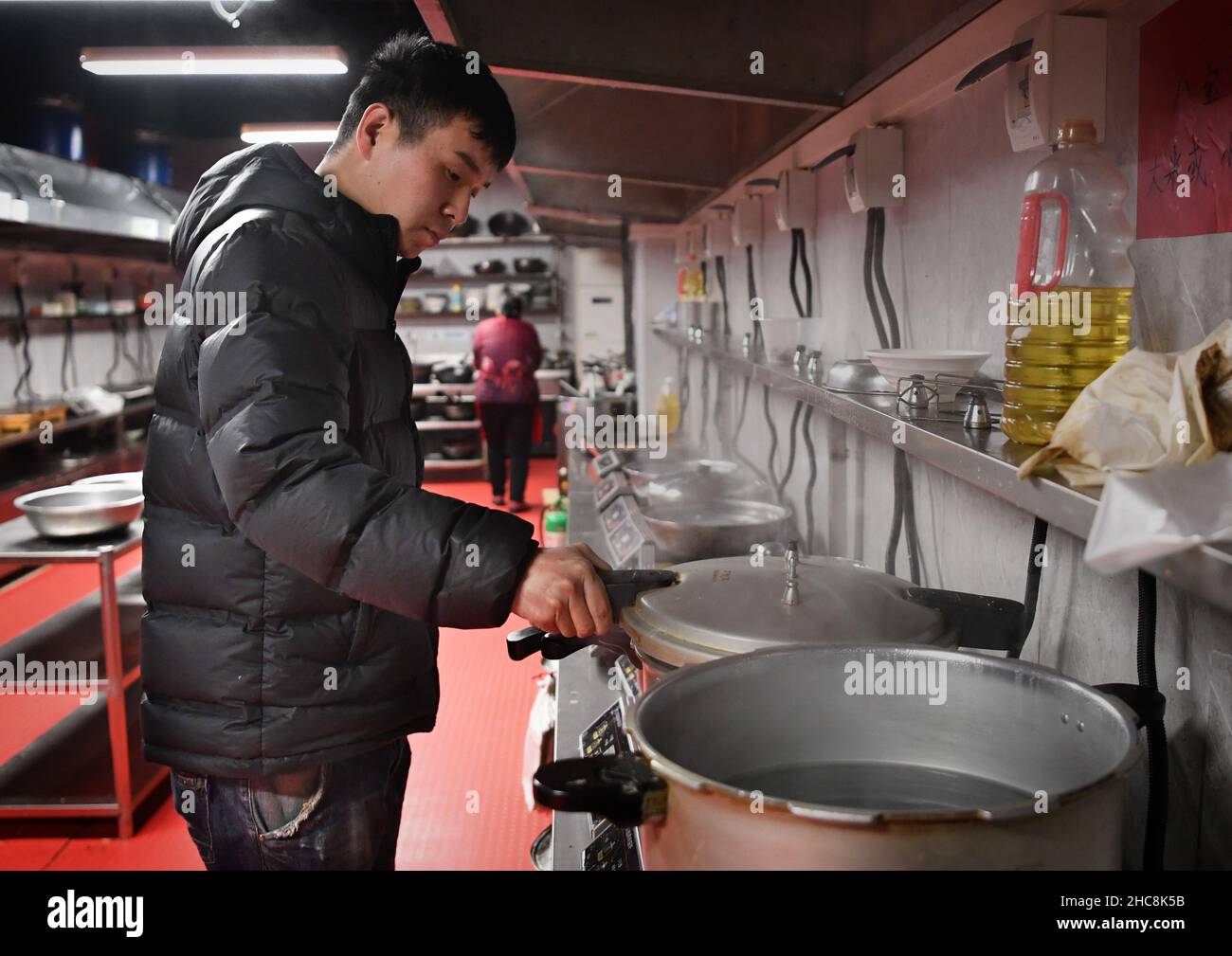 (211226) -- ZHENGZHOU, 26. Dezember 2021 (Xinhua) -- Zhang Guangbing kocht in seiner Gemeinschaftsküche in Zhengzhou, der Hauptstadt der zentralchinesischen Provinz Henan, am 14. Dezember 2021 freien Brei. Ein Mann in Zhengzhou, der Hauptstadt der zentralchinesischen Provinz Henan, betreibt eine Gemeinschaftsküche in der Nähe eines Krankenhauses für Krebserkrankungen. Nachdem er sich in einem Krankenhaus um seinen Vater gekümmert hatte, beschloss Zhang Guangbing 2014, die Küche für die Familien der Patienten zu öffnen, um Mahlzeiten zuzubereiten. „Ich kenne die Nöte von Familien mit Krebspatienten gut, die ihre Energie, Kraft und Geld nach und nach in dem langwierigen Prozess der medizinischen tr ausschöpfen Stockfoto