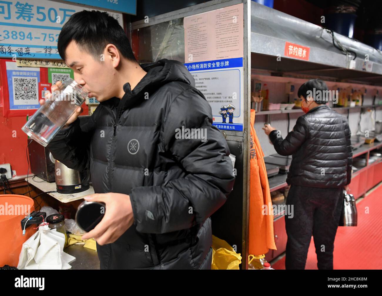 (211226) -- ZHENGZHOU, 26. Dezember 2021 (Xinhua) -- Zhang Guangbing trinkt während einer Pause in seiner Gemeinschaftsküche in Zhengzhou, der Hauptstadt der zentralchinesischen Provinz Henan, am 14. Dezember 2021 Wasser. Ein Mann in Zhengzhou, der Hauptstadt der zentralchinesischen Provinz Henan, betreibt eine Gemeinschaftsküche in der Nähe eines Krankenhauses für Krebserkrankungen. Nachdem er sich in einem Krankenhaus um seinen Vater gekümmert hatte, beschloss Zhang Guangbing 2014, die Küche für die Familien der Patienten zu öffnen, um Mahlzeiten zuzubereiten. „Ich kenne die Nöte von Familien mit Krebspatienten gut, die ihre Energie, Kraft und Geld nach und nach in dem langwierigen Prozess von mir ausschöpfen Stockfoto