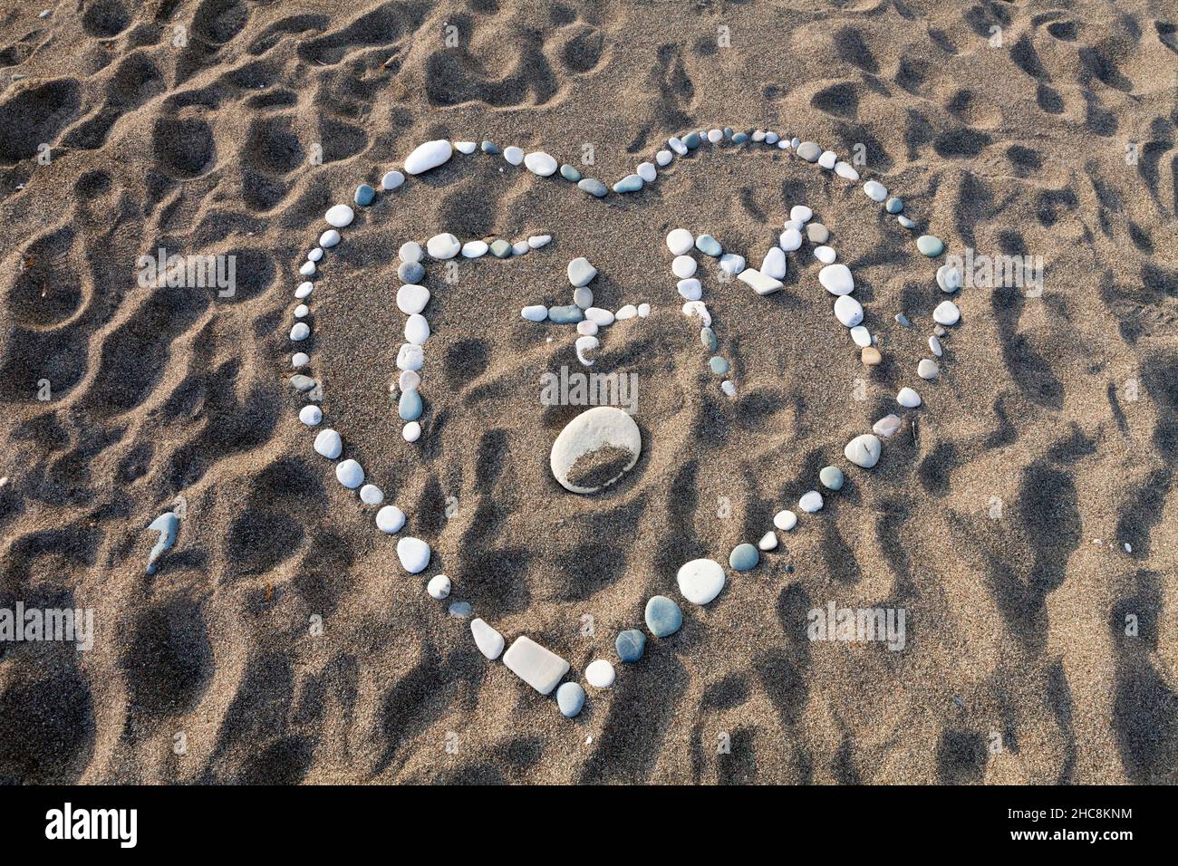 Liebesherz, mit Initialen eines Paares, geformt aus Kieselsteinen, am Sandstrand, Insel Zypern, östliches Mittelmeer Stockfoto