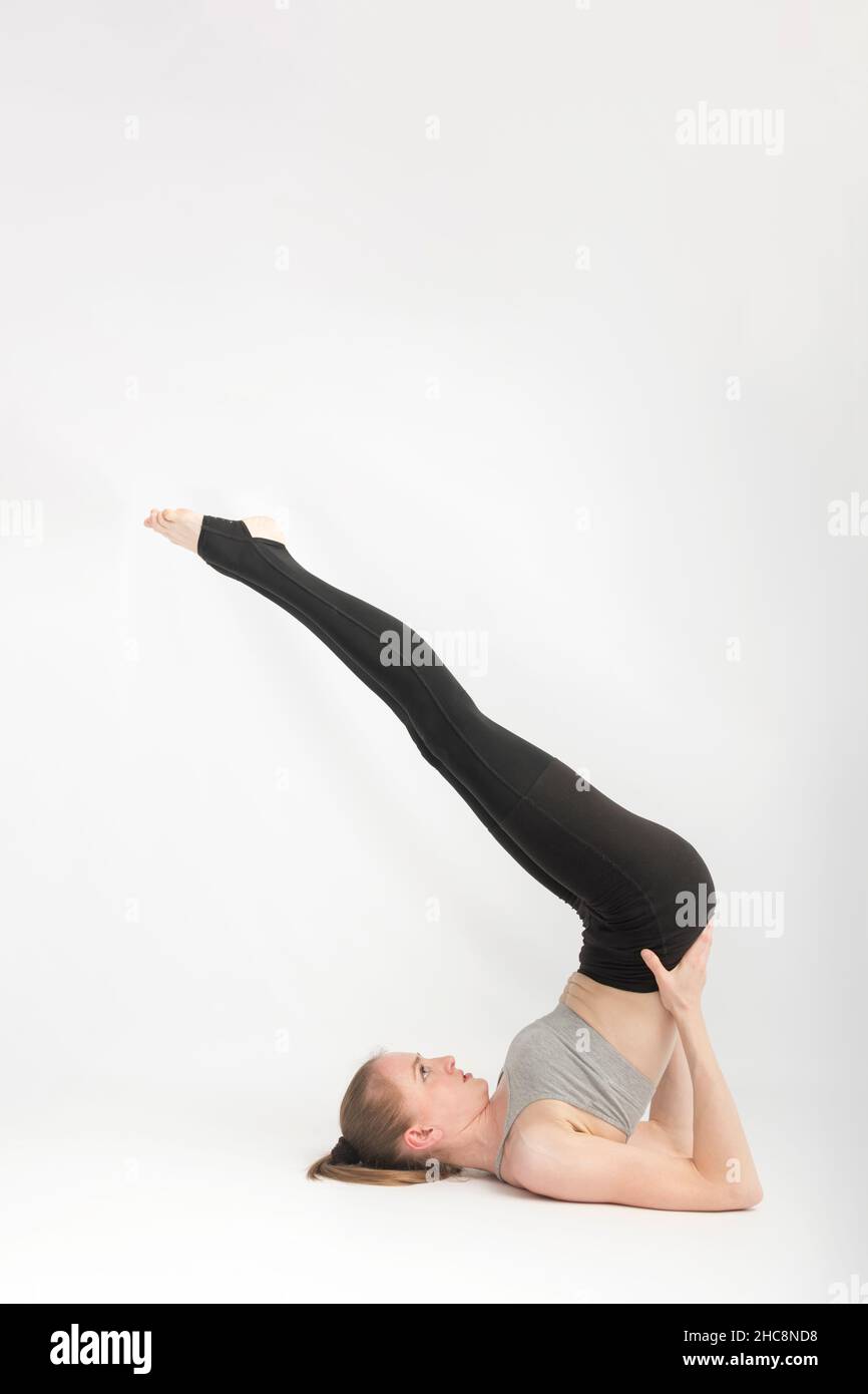 Viparita Karani. Salamba Sarvangasana. Unterstützter Shoulderstand. Junge schlanke Frau führt Yoga-Asanas. Hatha Yoga-Kurse. Vertikaler Rahmen Stockfoto