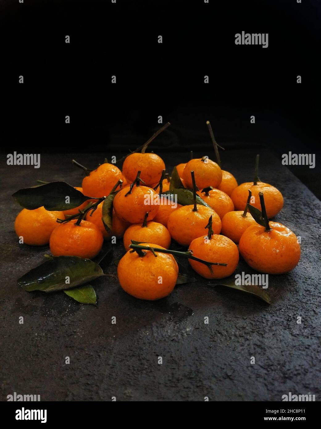 Mandarinen auf einem schwarzen Tisch mit schwarzem Hintergrund Stockfoto