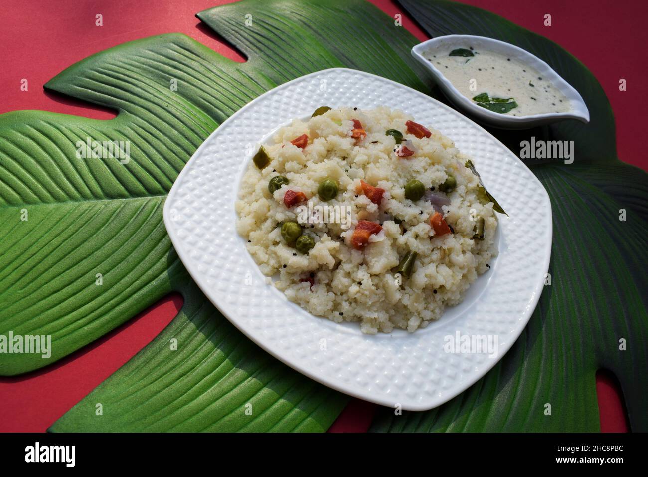 Leckeres indisches Frühstück mit Gemüse-Upma, serviert mit Kokosnuss-Chutney auf grünem Blatt. südindisches gesundes Frühstück aus rava oder Grieß mit Chopp Stockfoto