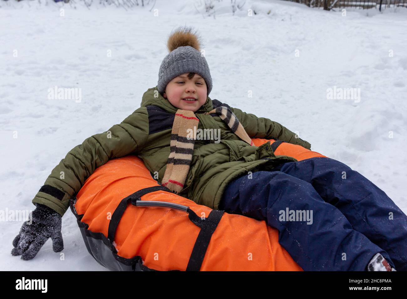 Junge, der einen Schlauch reitet. Winterspaß beim Skifahren auf dem Schneehügel Stockfoto