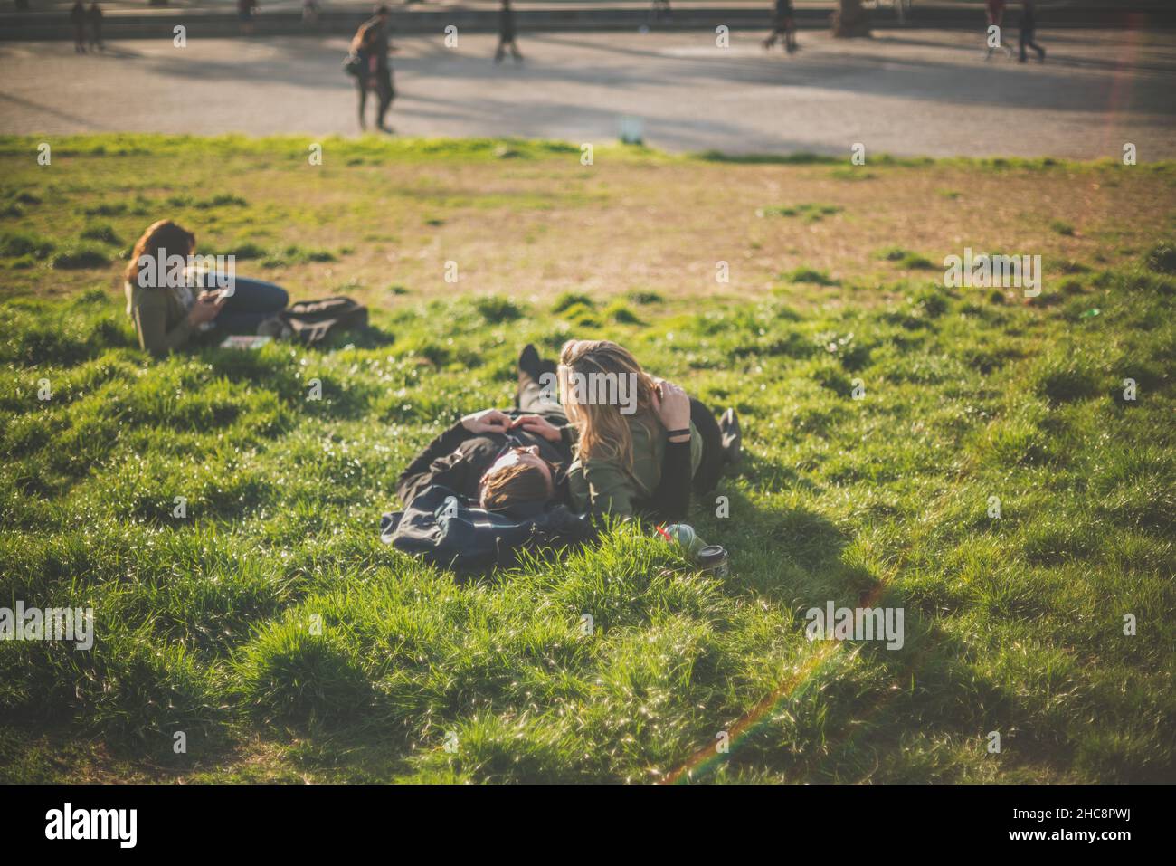 Strahlender Sommertag in einem Park mit einem Paar, das auf dem üppigen Gras liegt und den Tag genießt Stockfoto