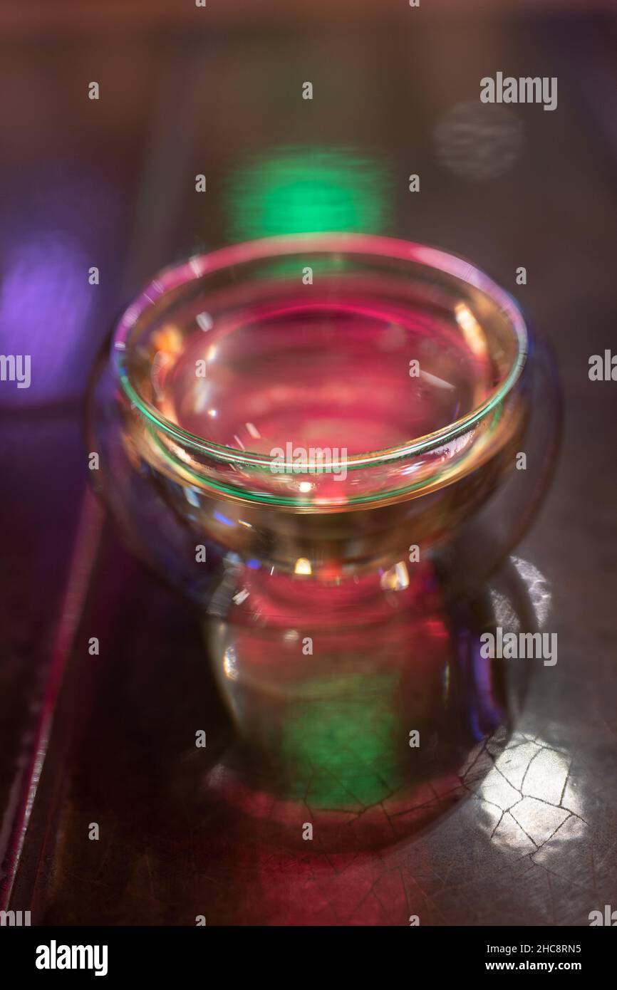 Gläser für heiße Getränke über verschwommenem Hintergrund, buntes Neonlicht. Reinigen Sie die Teetate. Stockfoto